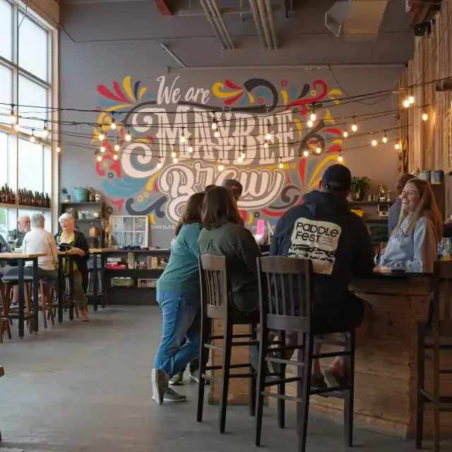 People socializing in a cozy coffee shop with colorful wall art and warm lighting.