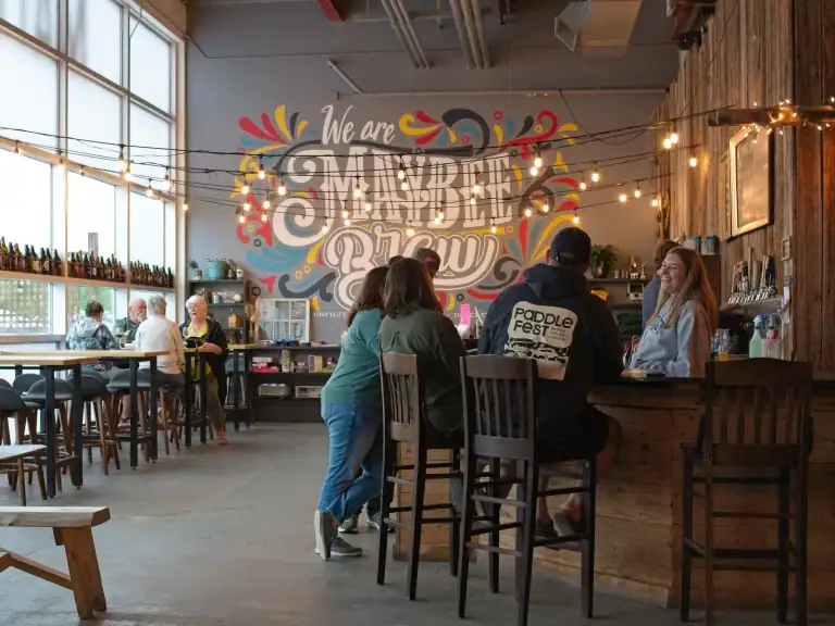 People socializing in a cozy coffee shop with colorful wall art and warm lighting.