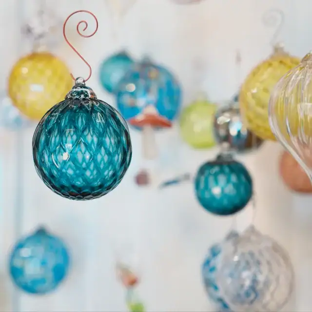 A collection of vibrant glass ornaments in blue, yellow, and clear, hanging from a string, perfect for holiday decorations or festive displays.