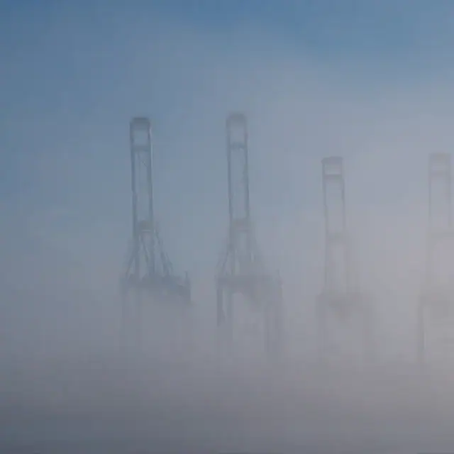 Four oil rig structures partially obscured by dense fog, creating a mysterious and atmospheric scene at sea.